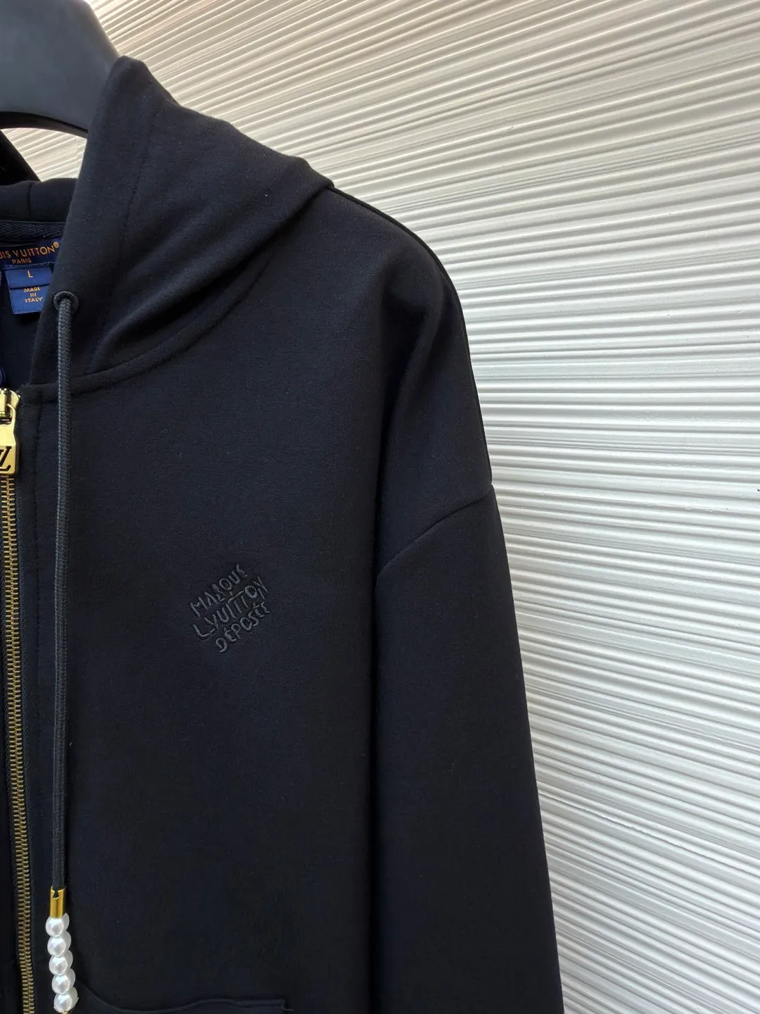 LOUIS VUITTON Pearl Pendant Zipper Jacket ●Original version: Purchased and developed for 10999 ●Item number: 1682253-B60 ●Fabric: wool blended fabric ●Technology: knitted embroidery production ●Color: black ●Version: fitted version ●Weight: about 715 grams ●Size: S-M-L-XL ●Description: This Louis Vuitton black hooded zipper sweatshirt is made of high-weight pure cotton waffle fabric. The fabric has been combed and singed, with a uniform and fine surface texture. It is also treated with anti-pilling and pre-shrunk, making it soft to the touch and not easily deformed after long-term wear. The brand logo on the left side of the body adopts the same color dark pattern embossing process and is hot-pressed through a temperature-controlled mold. The pattern is low-key and has a strong three-dimensional effect. The drawstring is embellished with custom-made pearl decorations, which are fixed by hand-beading. The surface of the pearls is polished to have a good luster and will not fall off easily. The metal zipper is made of gold-plated brass and has been treated with antioxidant treatment. The chain head is engraved with the brand's classic logo, making it smooth and wear-resistant. The ribs on the cuffs and hem are made of spandex blended material, which has excellent resilience and is not easy to loosen. The overall design is cut with loose shoulders, combined with double-needle hemming and seamless splicing technology. The stitching is fine and flat, which not only ensures comfort, but also shows the exquisite craftsmanship and brand texture of high-end garments. The overall wiring is straight and delicate, the fabric is comfortable and soft, and the color is consistent without color difference. It can be matched with the same style to create a fashionable look and control various occasions. Customized accessories, complete with three standards, same style for men and women!